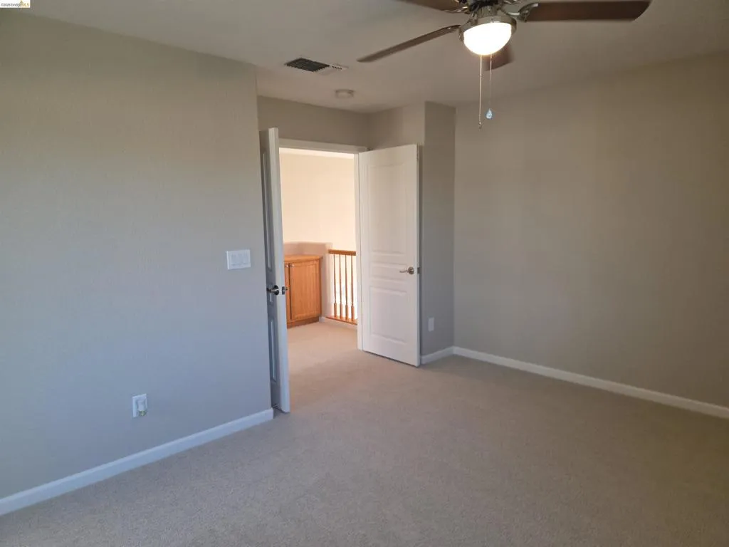 Carpeted room with neutral wall tones and a ceiling fan with integrated lighting