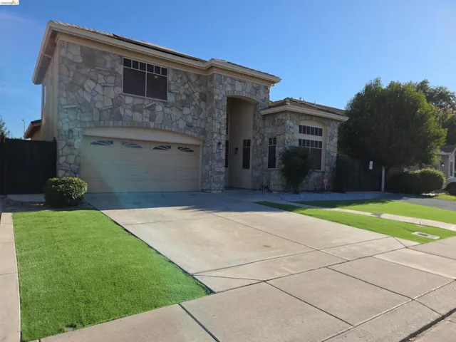 Stone-clad exterior featuring a two-car garage with an arched opening