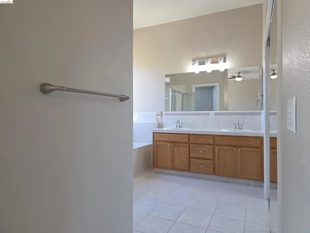 Double vanity with wood-finish cabinetry, dual undermount sinks, and a full-width mirror