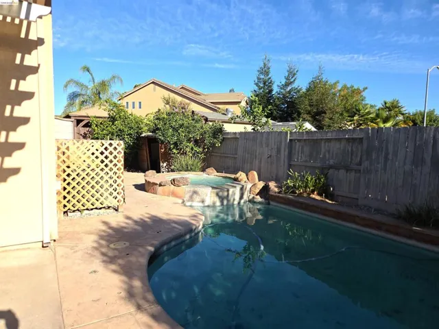 Inviting outdoor space featuring a swimming pool with an integrated spa, concrete patio surround, and privacy fencing