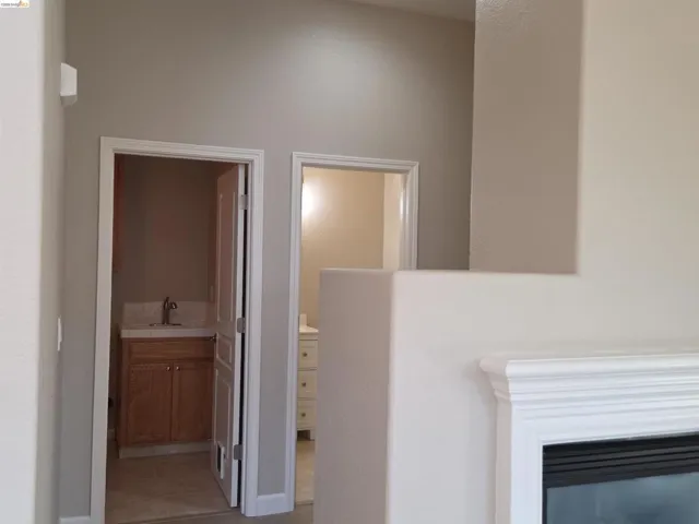 Integrated fireplace with a white mantel, two separate entries to rooms, light neutral wall paint, and white trim work
