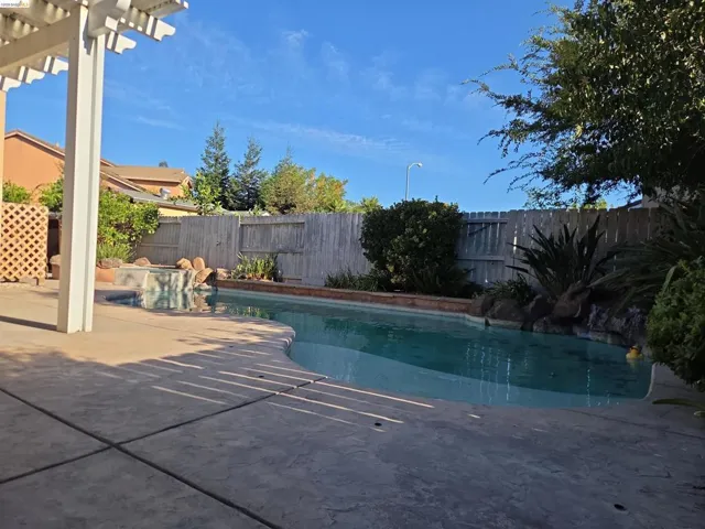 Outdoor living area featuring a swimming pool, integrated spa, and concrete patio