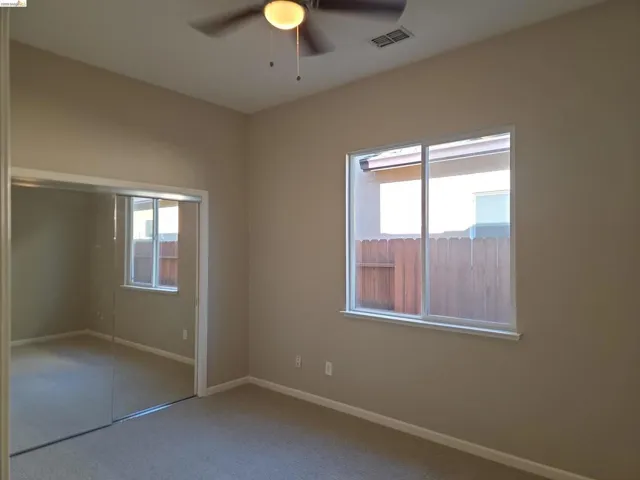 Room featuring a ceiling fan with integrated lighting, a sliding window with white trim, and mirrored closet doors