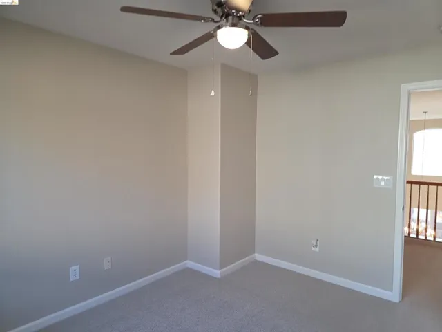 Carpeted room with neutral wall tones and white baseboards