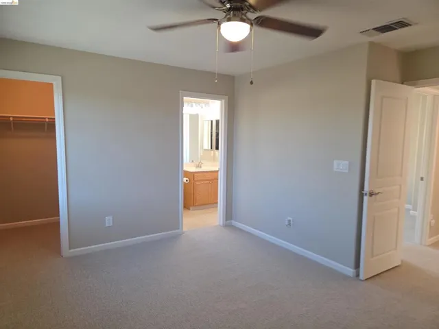 Carpeted room with a ceiling fan light fixture