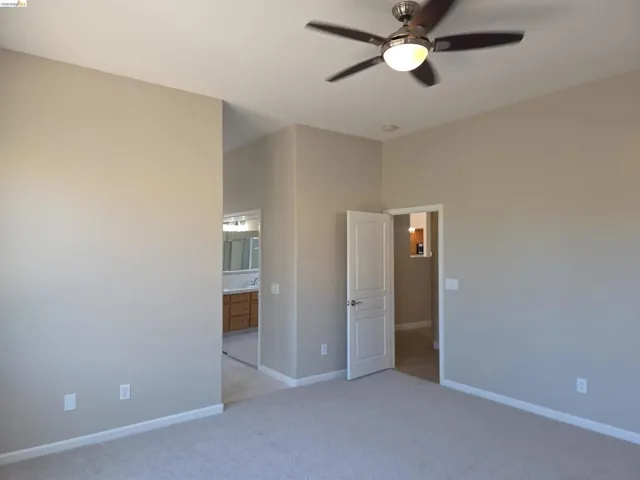 Carpeted interior space featuring a ceiling fan with light fixture