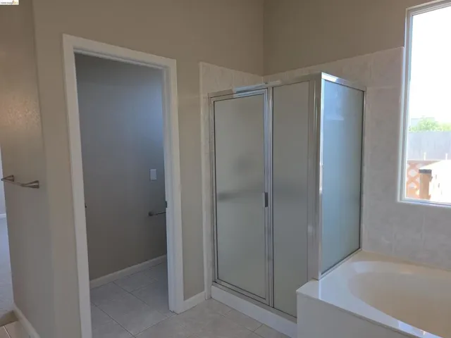 Frosted glass shower enclosure with chrome framing, featuring a built-in tub with a tiled surround