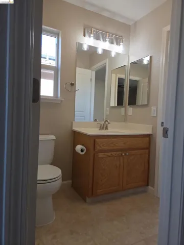 Bathroom featuring a single vanity with wood-finish cabinetry, a white countertop, and a chrome faucet