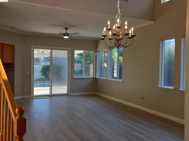 Spacious interior featuring wood-finish flooring, a contemporary ceiling fan, and an ornate chandelier