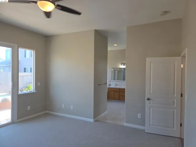 Carpeted room featuring a ceiling fan, sliding glass door, and a single window