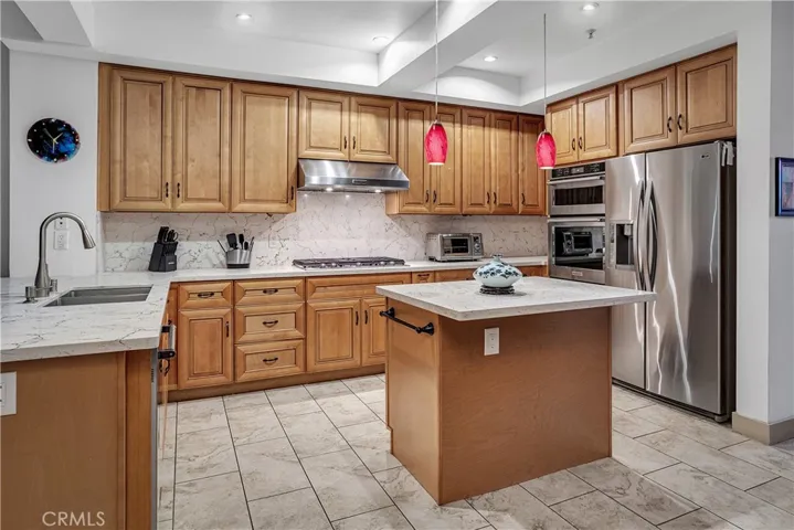 Remodeled kitchen with extensive cabinetry, quartz surfaces, center island, and premium stainless steel appliances.