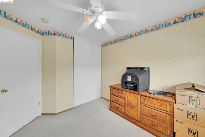 Bedroom featuring light-toned carpeting, a ceiling fan with integrated lighting, and a white door with brass-finish hardware