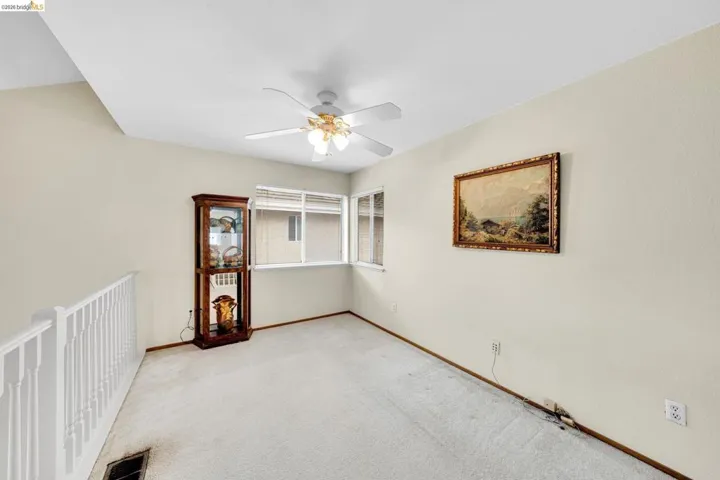 Room featuring a vaulted ceiling with a ceiling fan, light-colored walls, and carpet flooring