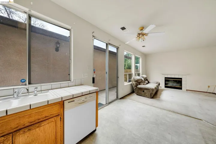 Open concept living area with a fireplace featuring a tile surround and mantel