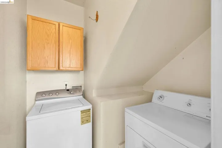 Dedicated laundry area featuring overhead wood-finish cabinetry