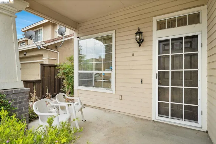Covered concrete patio featuring siding exterior, an exterior light fixture, and a window with white trim