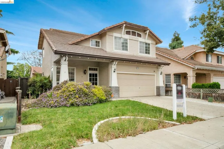 Two-story residence featuring a tile roof, an integrated two-car garage, and a covered front porch with decorative columns