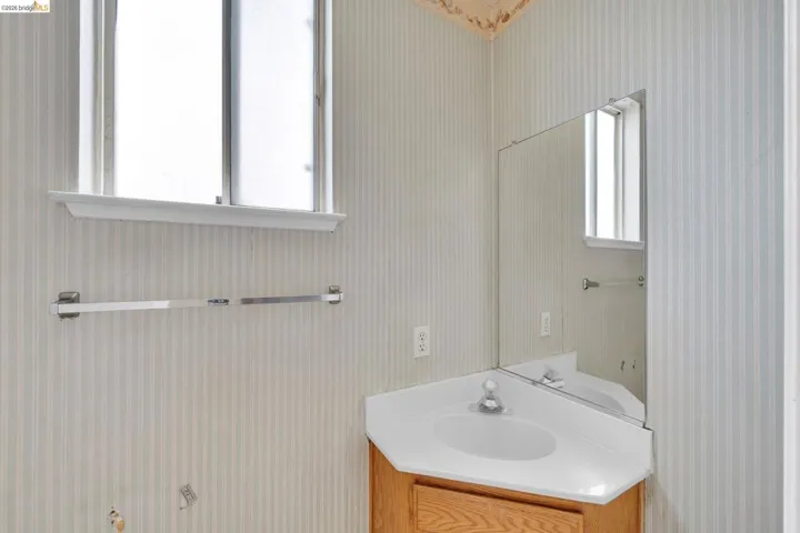 Corner vanity featuring a white integrated sink, chrome faucet, and wood-finish cabinetry