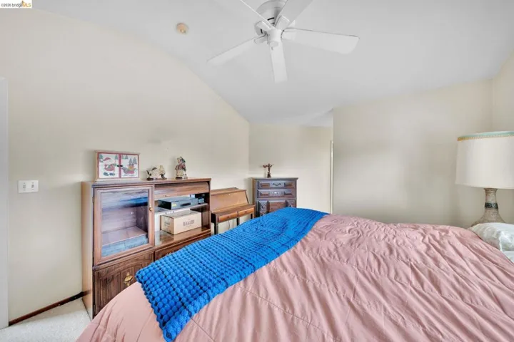 Vaulted ceiling featuring a ceiling fan, light-toned wall paint, and white trim