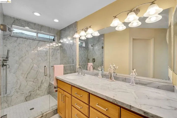 Dual vanity with light-tone wood cabinetry and a stone countertop