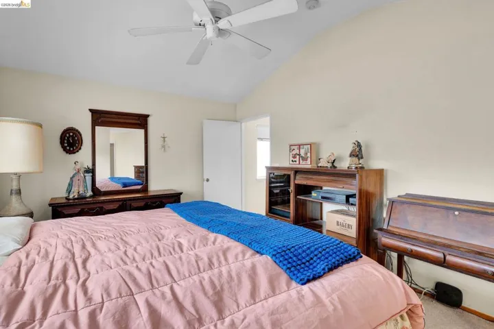 Vaulted ceiling room featuring a ceiling fan, light-toned walls, and white trim