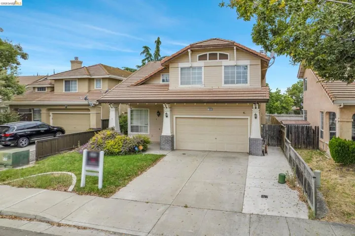 Two-story residence featuring a tile roof, an integrated garage, and a concrete driveway