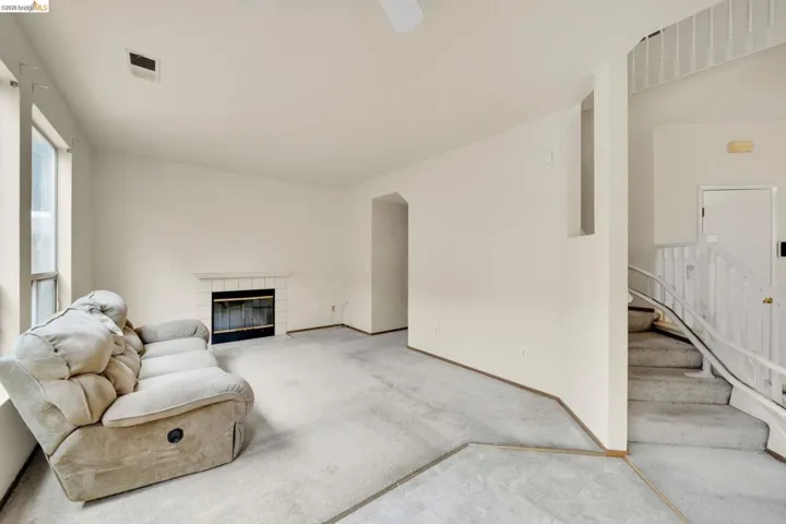 Living area featuring a fireplace with a white tile surround, vaulted ceilings, and large windows