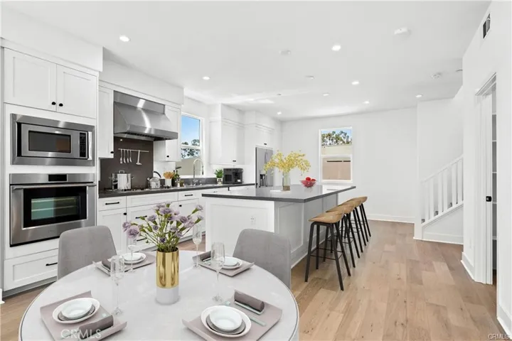 A large "eat at" island with room for at lease 4 bar stools, the flooring is the luxury vinyl, there is a built in microwave and oven, dishwasher, refrigerator, gas cooktop and lots of natural light