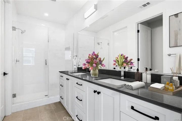 Spacious primary bathroom with 2 sinks, a walk-in shower, and lots of countertop & storage space.