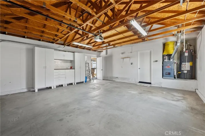A view of the garage showing the side door, cabinets, workbench and newer furnace / hot water heater.