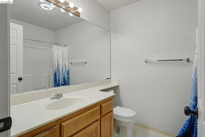 Bathroom featuring a single vanity with light-tone cabinetry, an integrated sink, and a spacious mirror