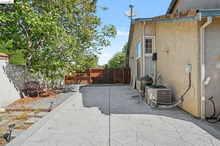 Stamped concrete patio area featuring stucco exterior, bay window, and a wood privacy fence