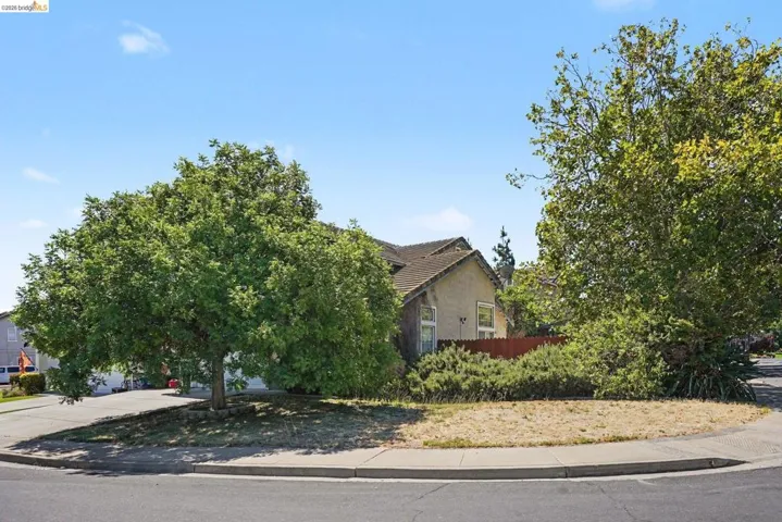 Two-story stucco property with a terracotta-style tile roof and mature trees