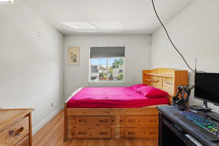 Bright interior room featuring wood-finish flooring and a window with blinds