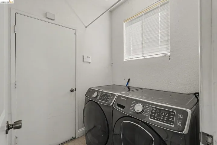 Laundry area featuring a window with blinds, a solid door, and textured walls