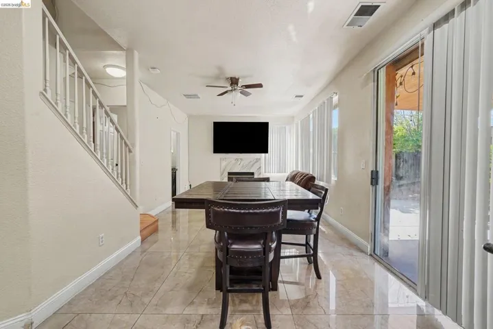 Spacious room featuring large format tile flooring, a contemporary fireplace with a stone surround, and multiple windows with vertical blinds