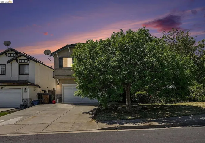 Two-story residence featuring a two-car garage, driveway, and mature landscaping