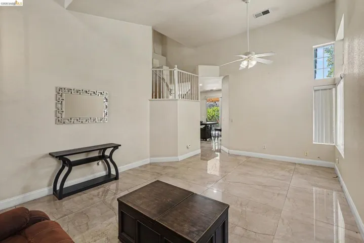 Spacious interior featuring vaulted ceilings, light-toned tile flooring, and a ceiling fan with integrated lighting