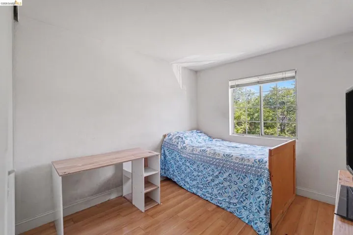 Room featuring wood-finish flooring, white walls, and a window with horizontal blinds