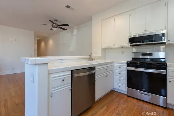 Crisp, white kitchen with stainless steel appliances.