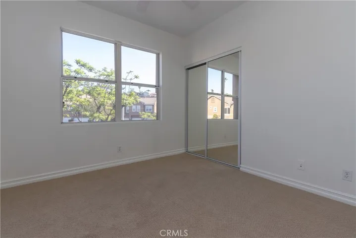 Secondary bedroom with large window and a mirrored closet with organizer.