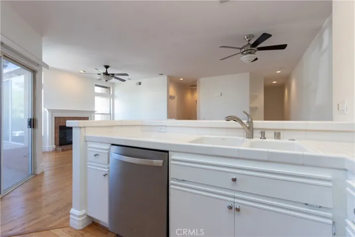 White counters and cabinets and a stainless steel dishwasher.