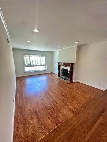 Spacious formal living room with recessed lights and huge window on the backyard side along with an elegant fireplace and mantle