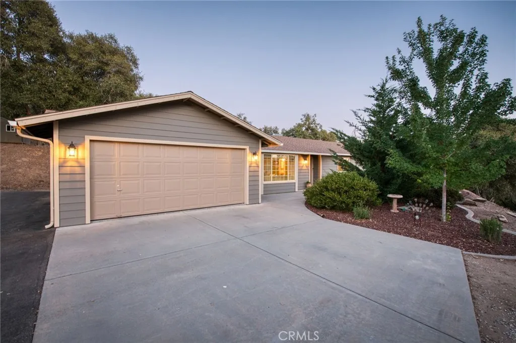 Clean concrete driveway leading to a spacious attached two-car garage with modern exterior lighting.