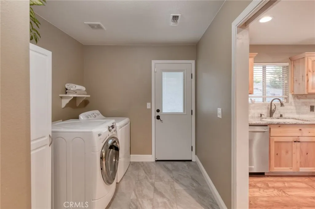 Dedicated indoor laundry and mudroom with direct exterior access, updated flooring, and extra storage capacity.