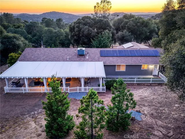 Stunning 3-bedroom mountain estate nestled on 2.7 private acres in Coarsegold, CA, glowing under beautiful twilight skies.