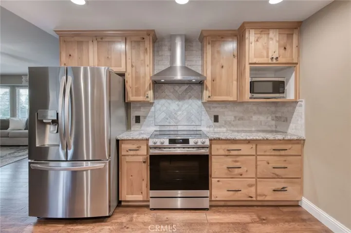 Premium stainless steel appliances, a modern range hood, ample counter space, and custom tile backsplash finishes.