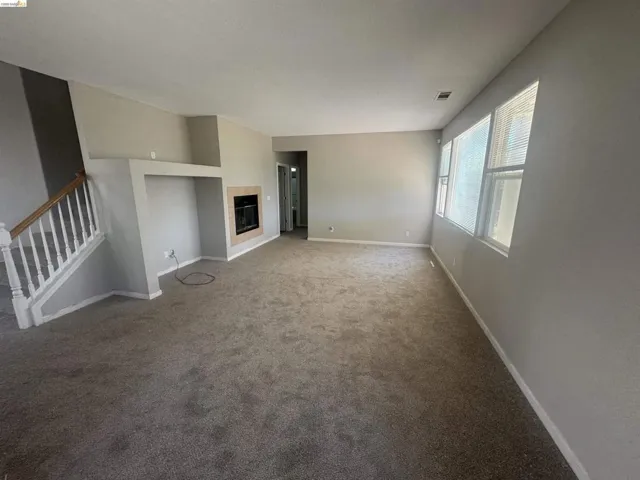 Unfurnished living room with a tile fireplace and carpet floors