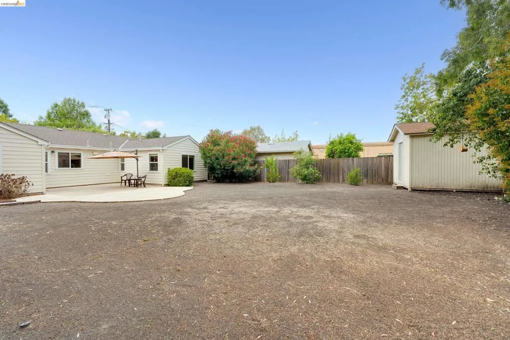 Spacious backyard with a large gravel area, a concrete patio, and a dedicated storage shed