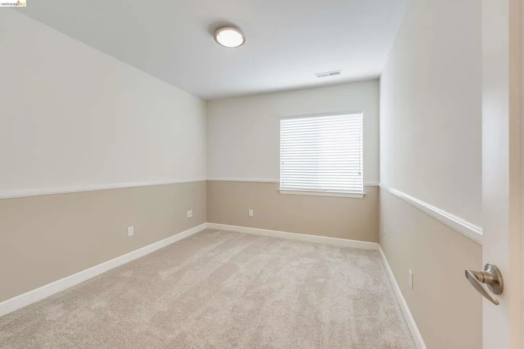 Carpeted interior space featuring a single window with blinds, a flush-mount ceiling light fixture, and two-tone wall finishes